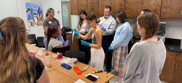 eDNA workshop attendees watching as someone demonstrates pipetting.