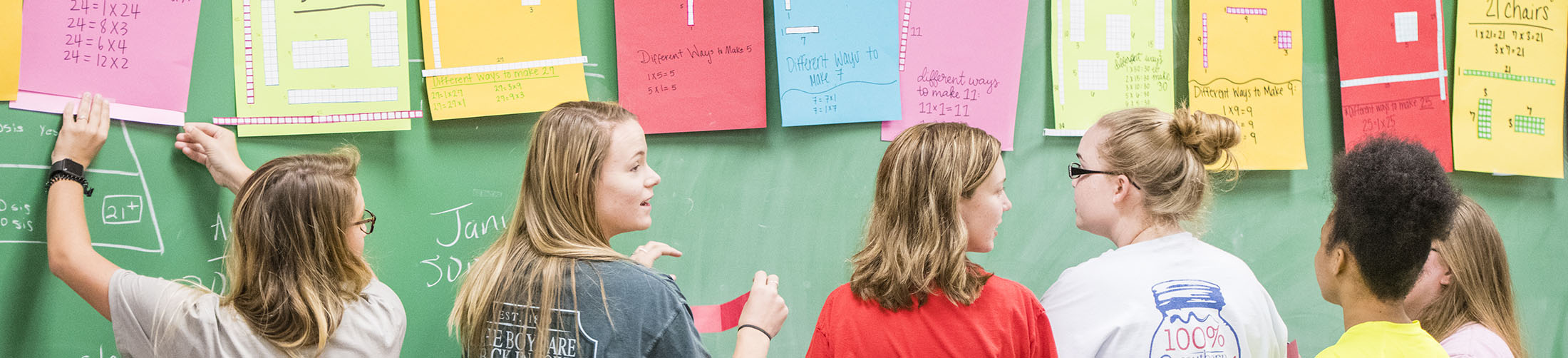 Student teachers working with children in classroom.