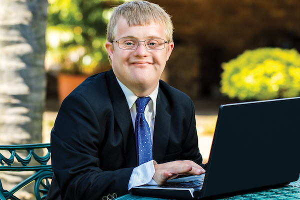 Student working on laptop outside on campus.