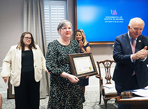 Camille Wilson holding her award presented to her by President Bonner.